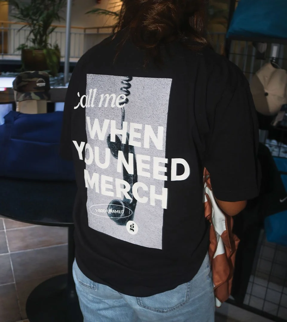 A shirt being worn, "Call me when you need merch" is the graphic.