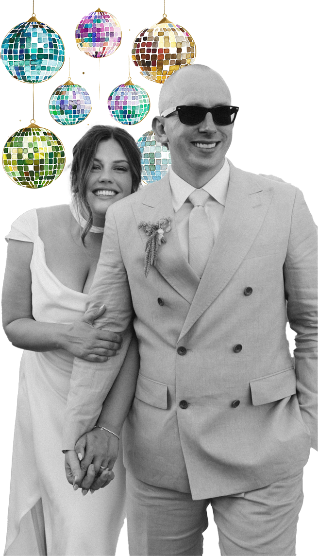 A black and white photo of a smiling couple holding hands, with colorful disco balls hanging above them.