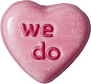 Pink heart-shaped candy with the words 'we do' embossed on it.