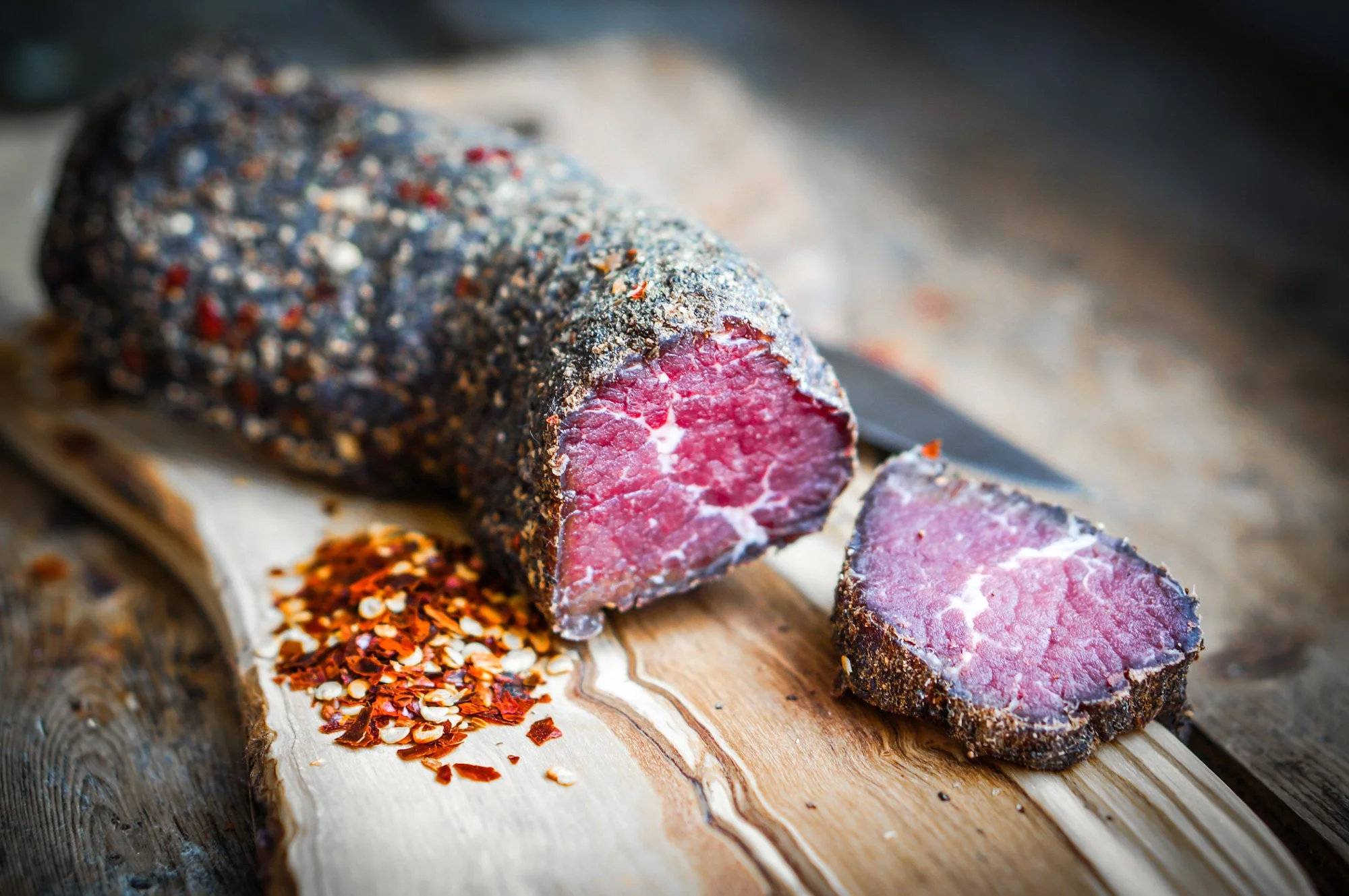 Rindfleischsalami mit Pfefferkörnern auf Schneidebrett