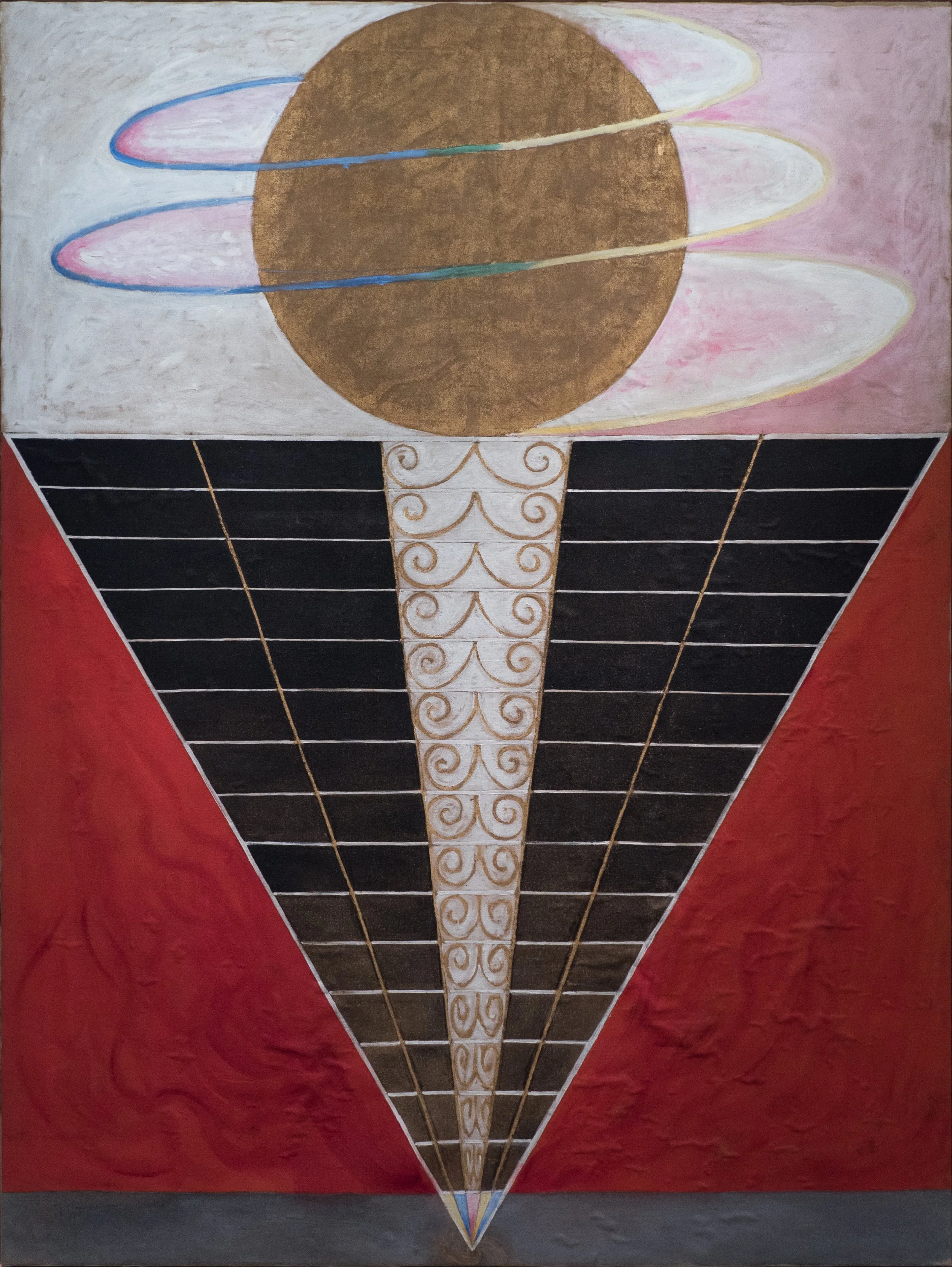 An artwork depicting an abstract hot air balloon with a large, brownish-golden sphere as the balloon. The balloon has a geometric design with black and white sections, accented by gold lines and swirls. The background features a gradient from white and pink on the upper part to red and gray at the bottom.