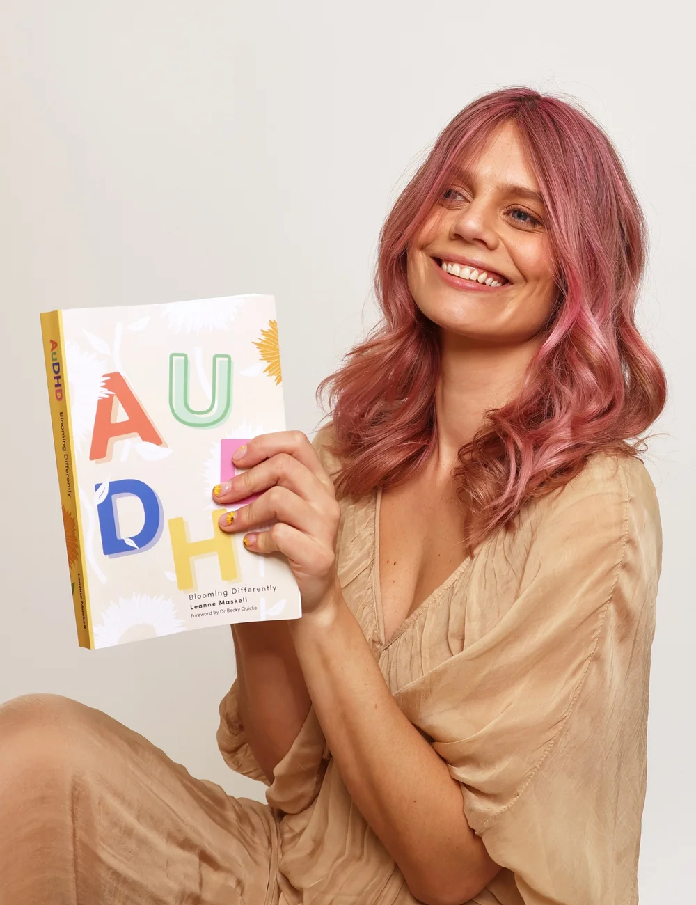 Leanne Maskell holding her book AuDHD: Blooming Differently
