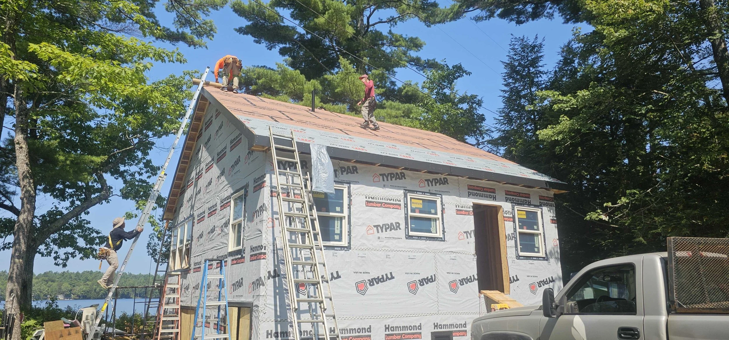 Maine Coast Roofing team installing a standing seam metal roof on a clear day in Maine