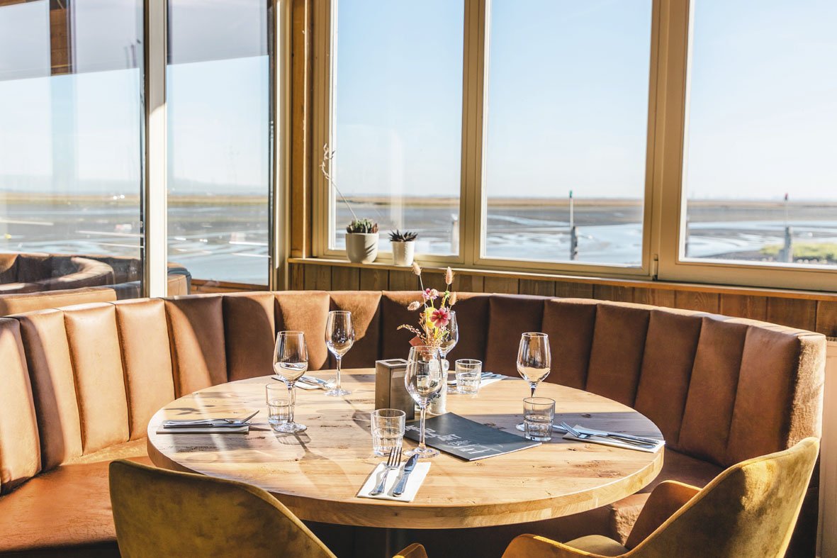 Gedekte ronde tafel aan het raam met uitzicht over het water