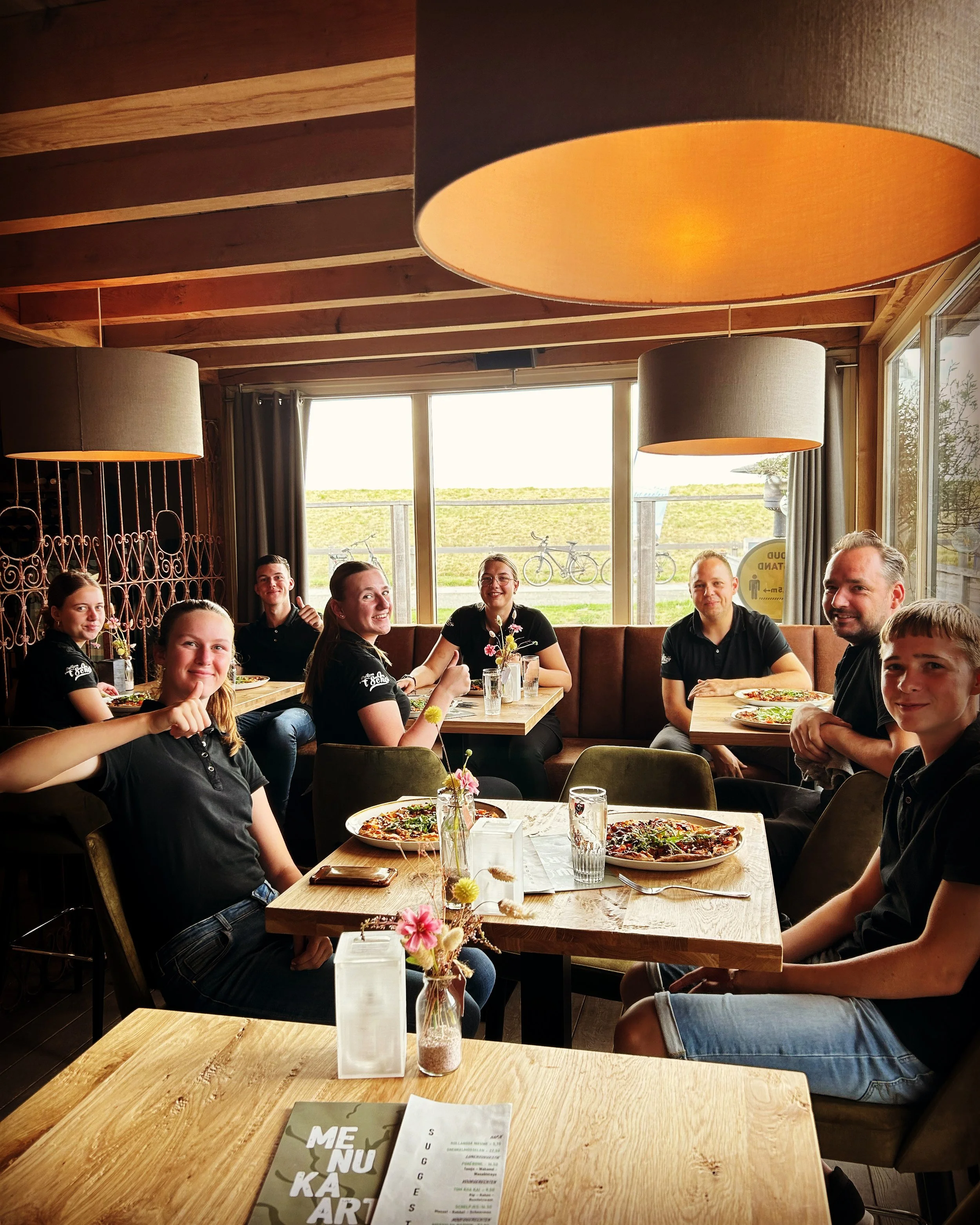 Gasten aan tafel in het restaurant van 't Schor met uitzicht op het water