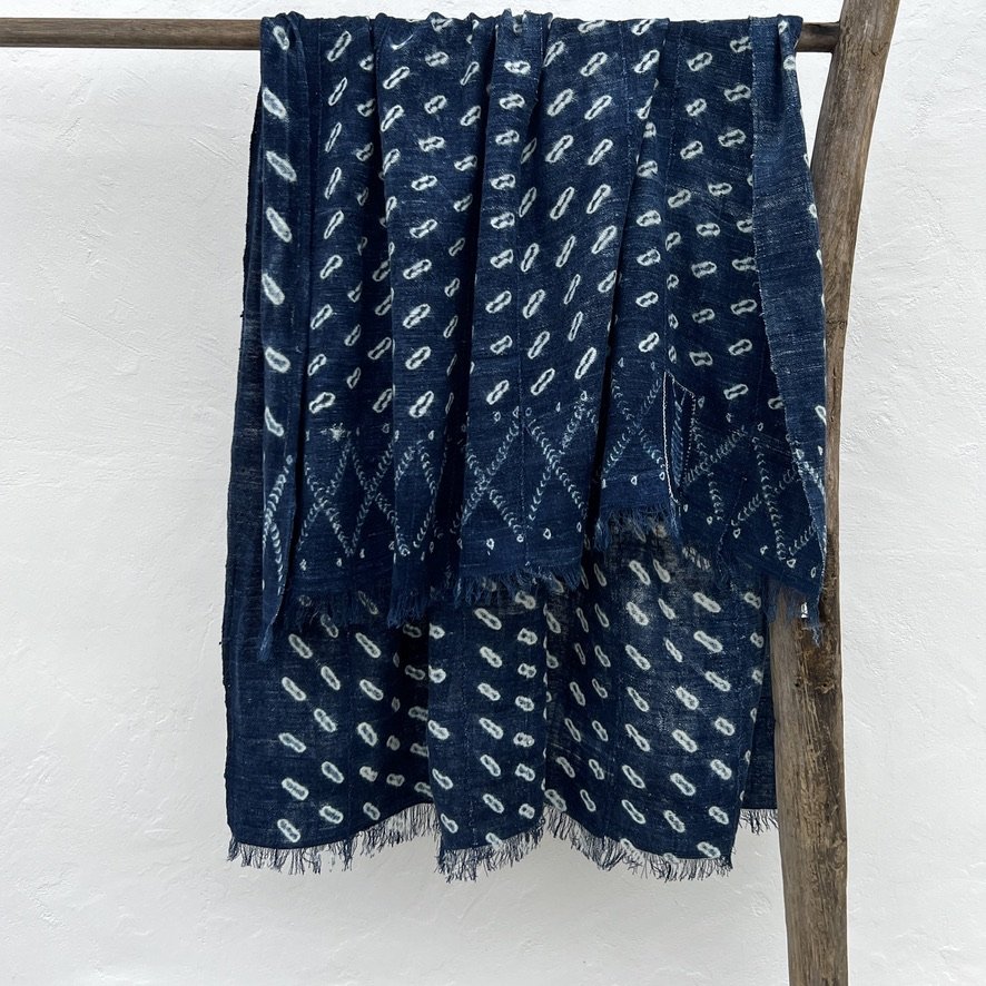 Indigo cloth cowrie shell visibly mended hanging bunched up