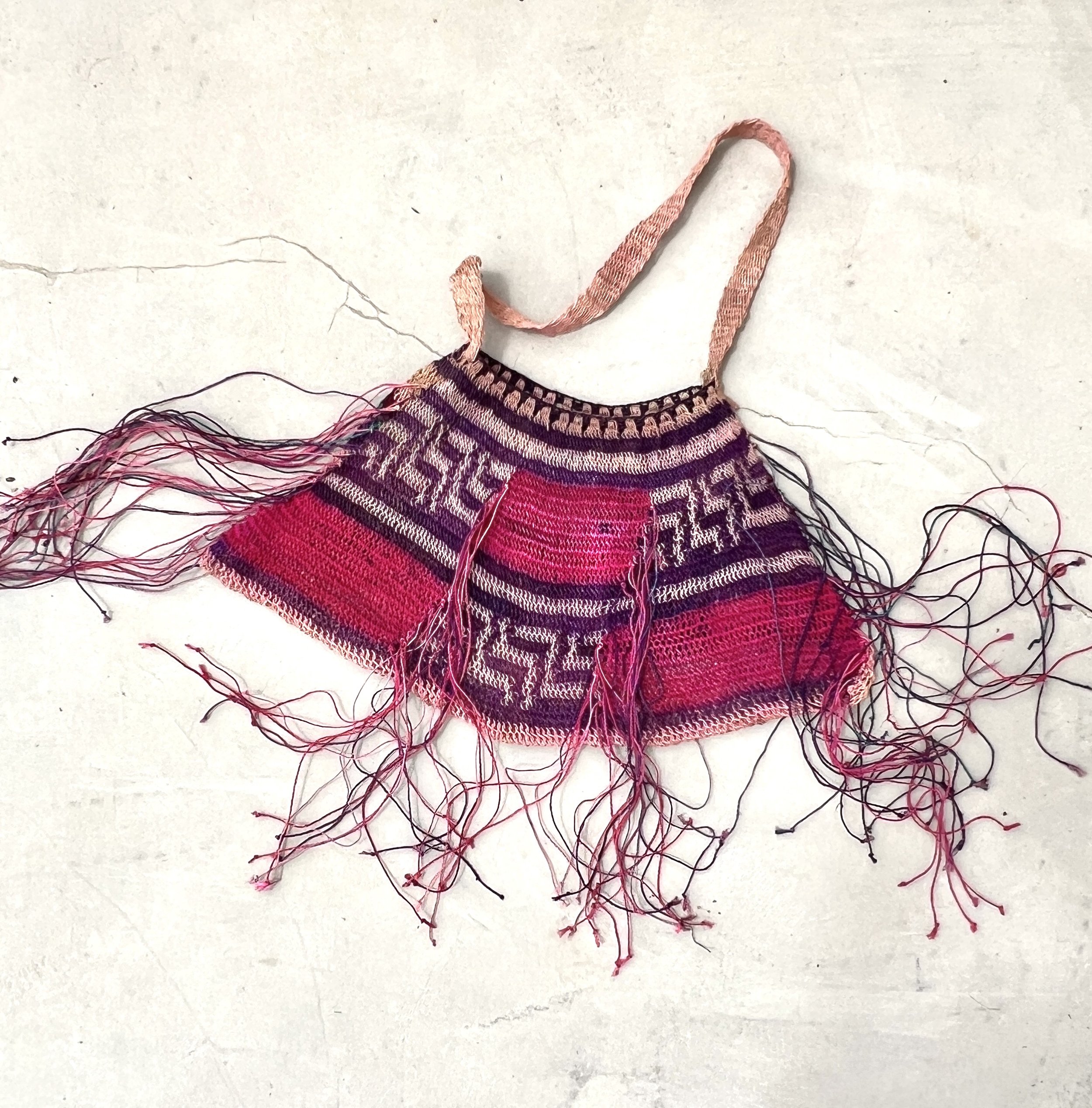 Pink Madang Bilum bag with fringe lying flat