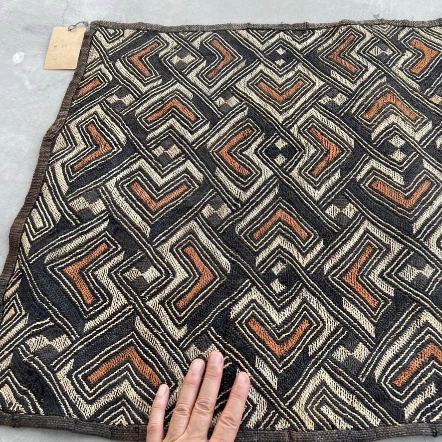Square Kuba cloth from Congo with heart pattern in black, brown and beige with corner with hand