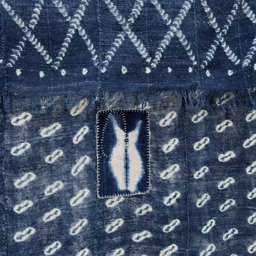 Indigo cloth cowrie shell visibly mended closeup 3