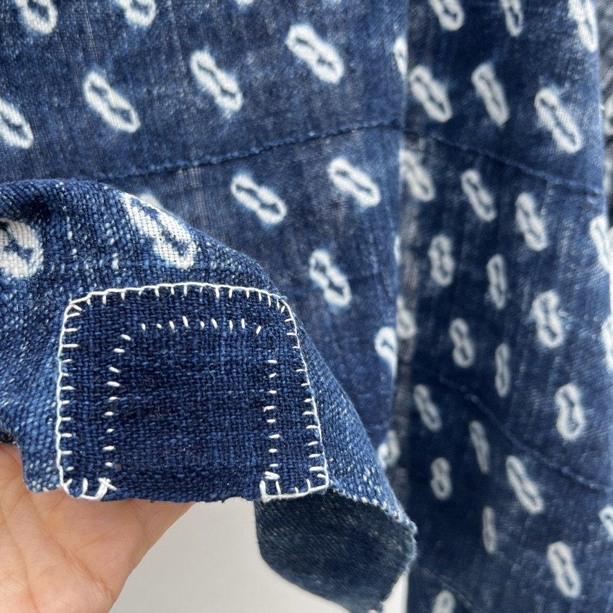 Indigo cloth cowrie shell visibly mended closeup 2