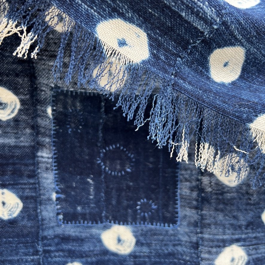 Indigo cloth dark blue cowrie shells visibly mended closeup patch