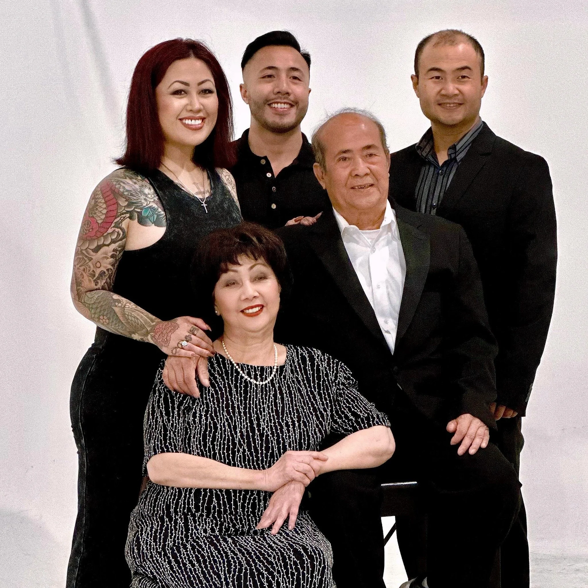 A family portrait featuring six members dressed in formal attire against a white background.