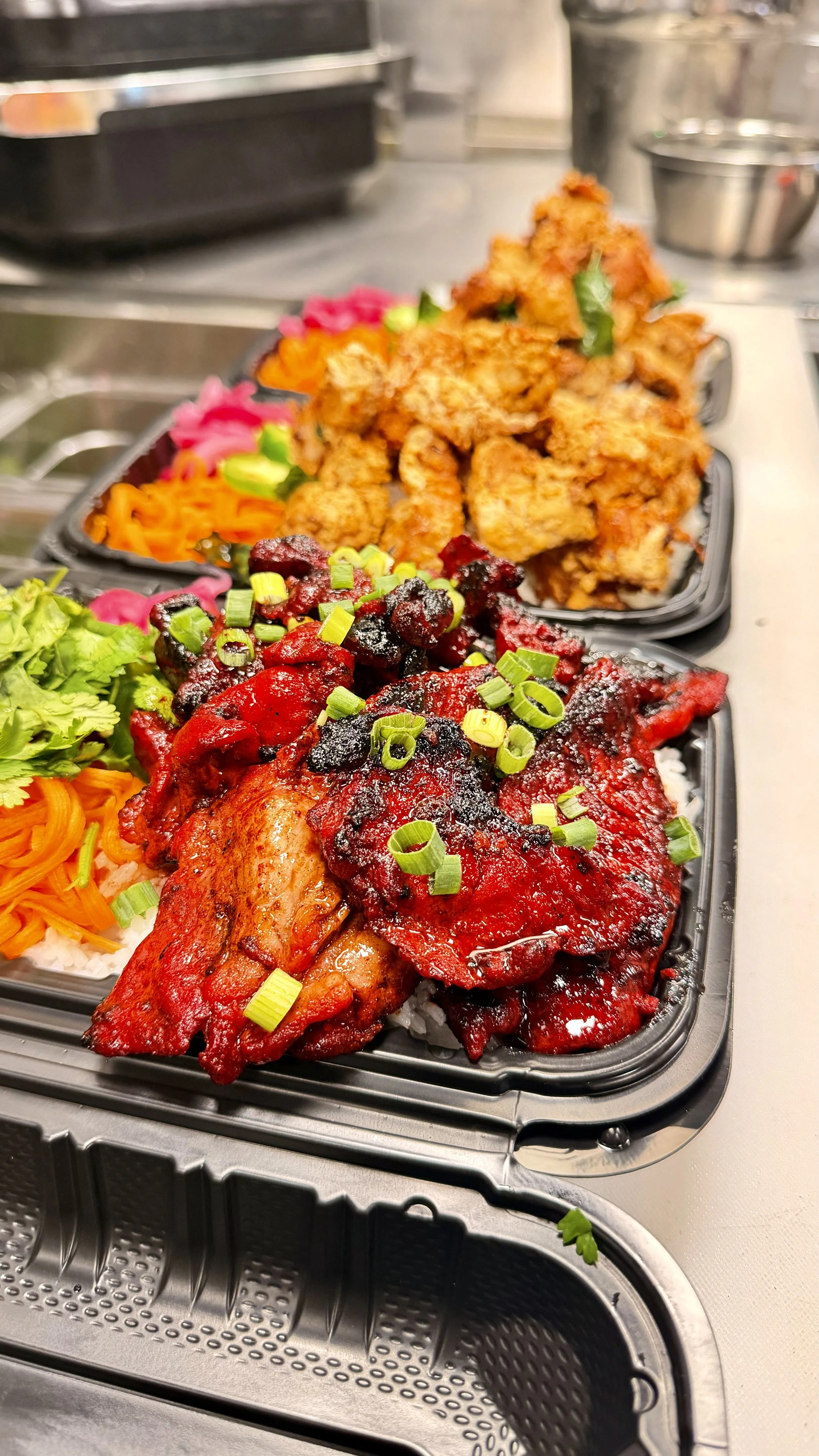 Takeout containers filled with Asian-inspired dishes, including glazed chicken with green onions, fried chicken, and assorted vegetables.