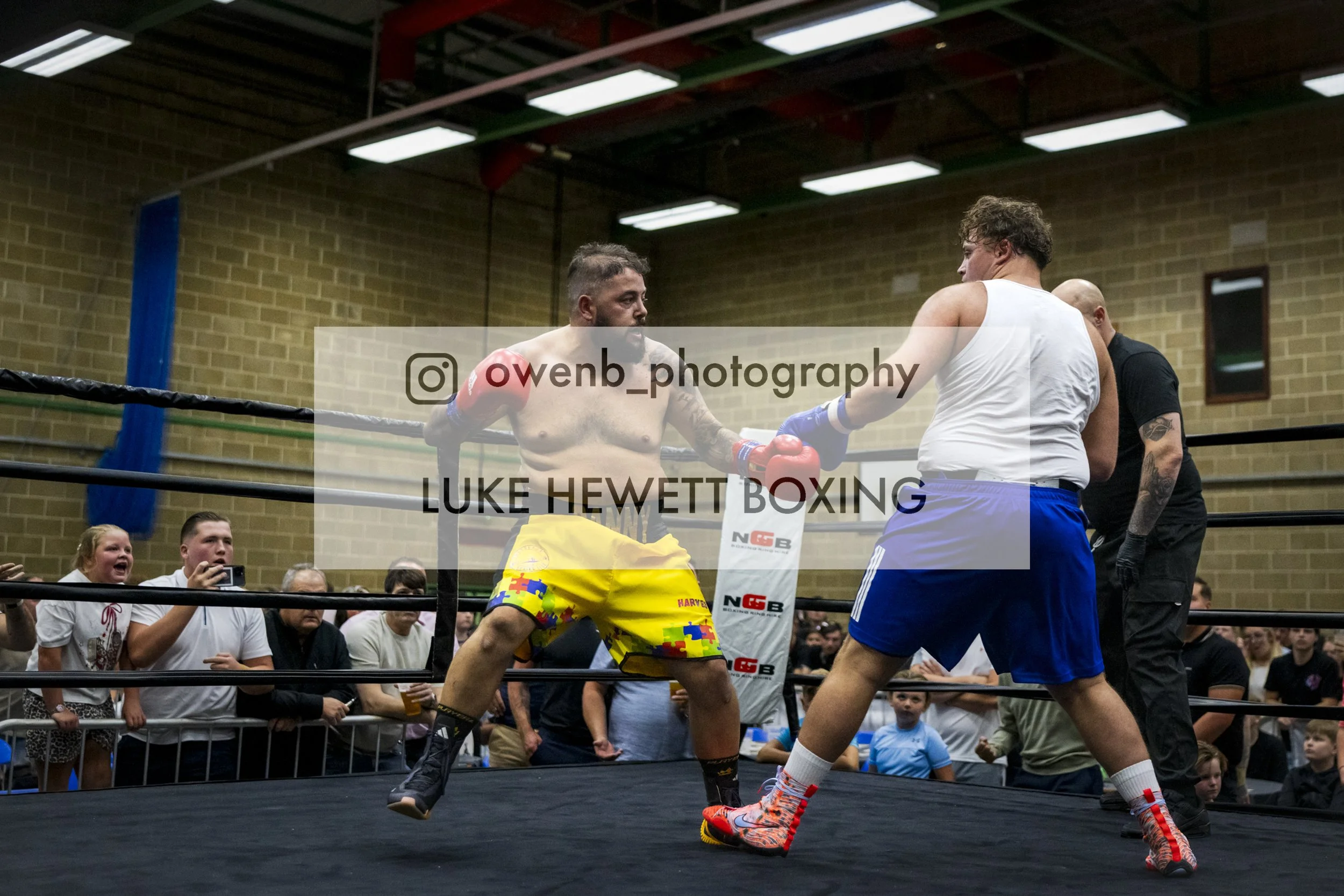 Boxing match with two fighters in ring and audience watching.