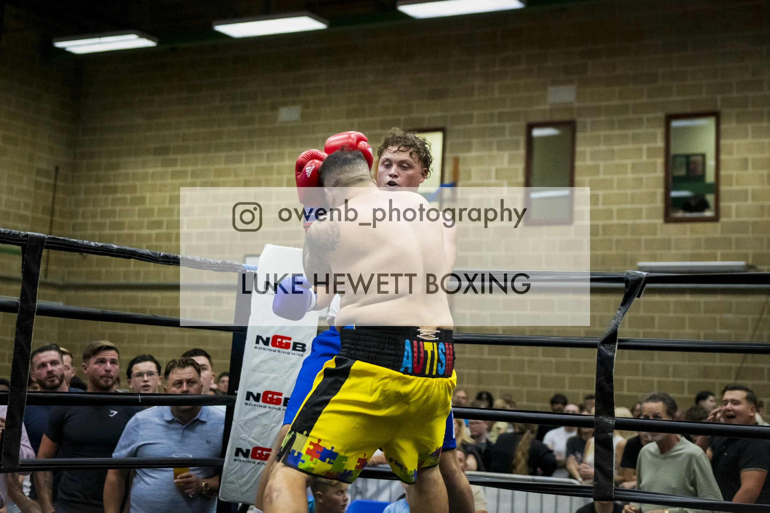 Boxer and opponent in a match inside a boxing ring with a crowd watching.