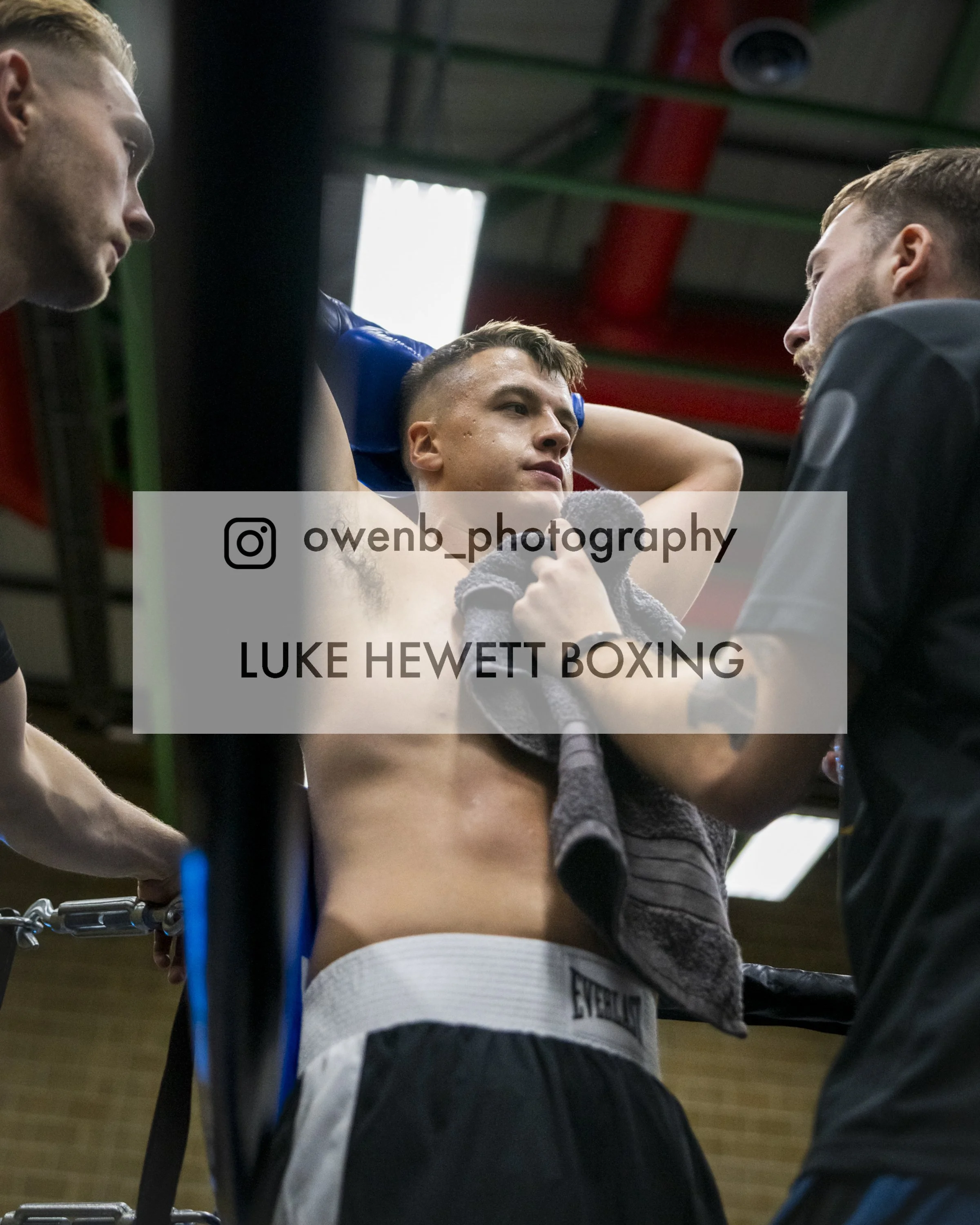 Boxer Luke Hewett receiving coaching and encouragement in a gym setting during training.