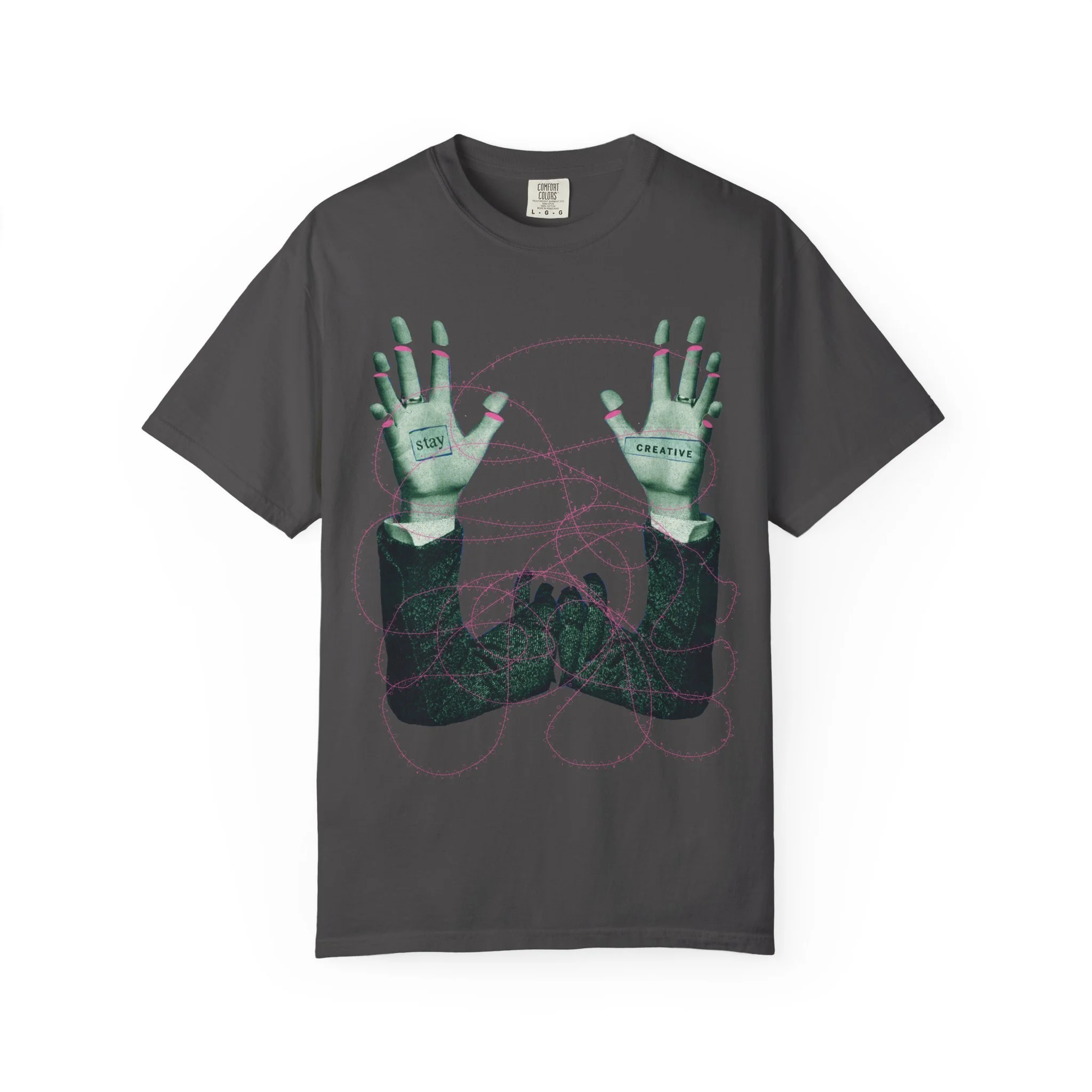 A lifestyle product shot of a unisex graphic t-shirt printed with a surrealist collage featuring text reading Stay Creative alongside vintage halftone imagery.