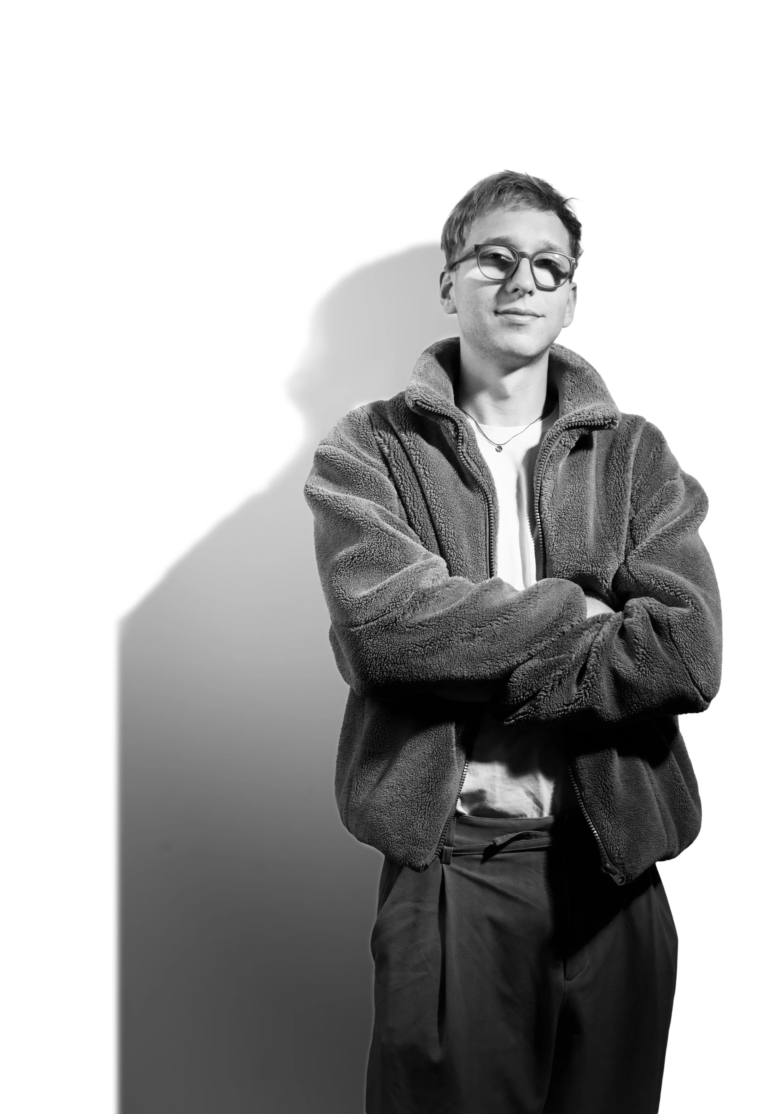 Schwarz-weißes Porträt einer jungen Person mit Brille und Fleecejacke vor hellem Hintergrund
