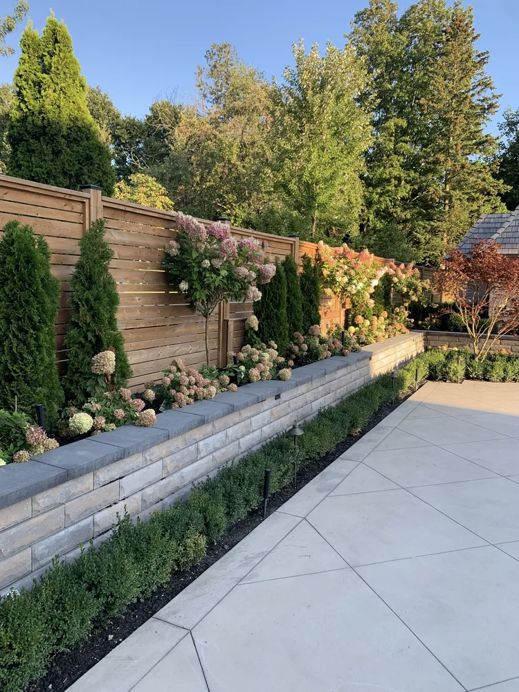 Cedar privacy fence, stone retaining wall and slab patio