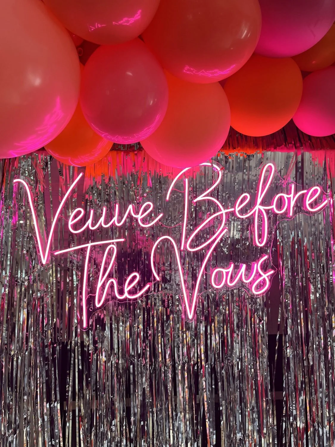 Pink and orange balloons around a Veuve Before Vows photo backdrop