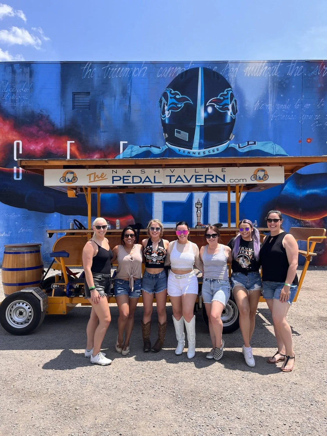 Bachelorette group posing beside a yellow Pedal Tavern in Nashville.