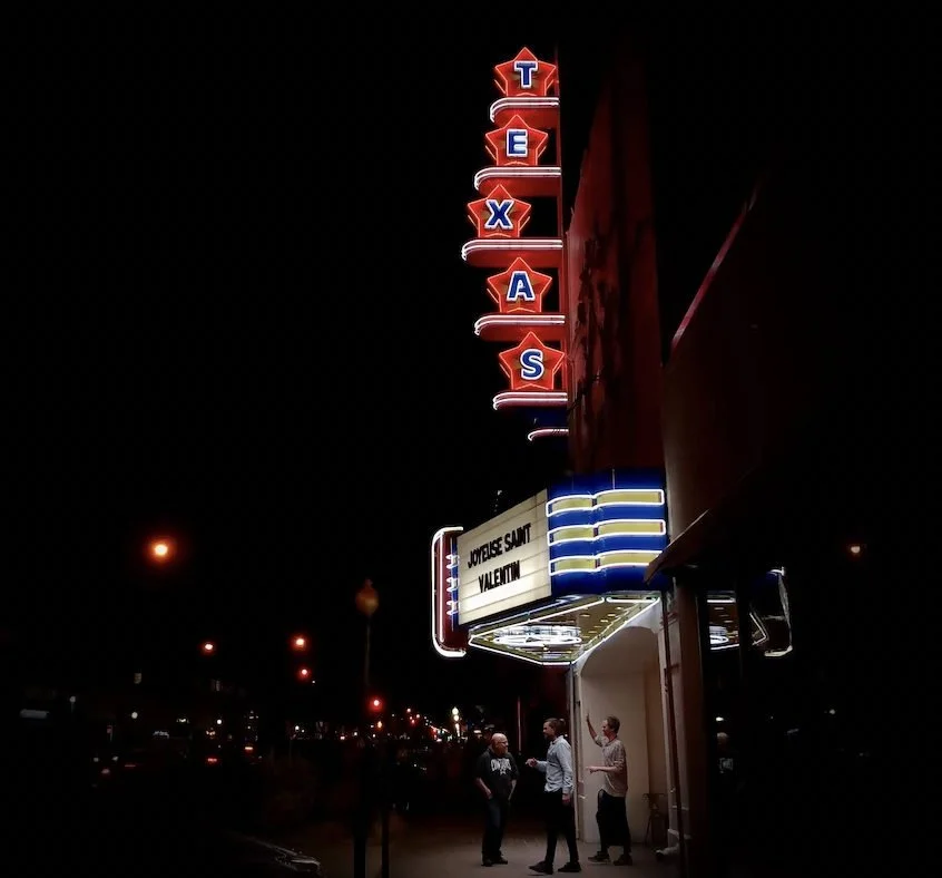 Illuminated Texas Theatre sign above a sidewalk at night.