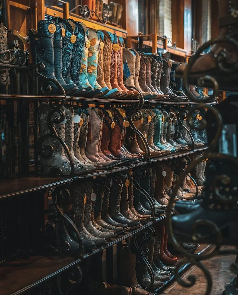 Rows of colorful embroidered cowboy boots displayed on store shelves.
