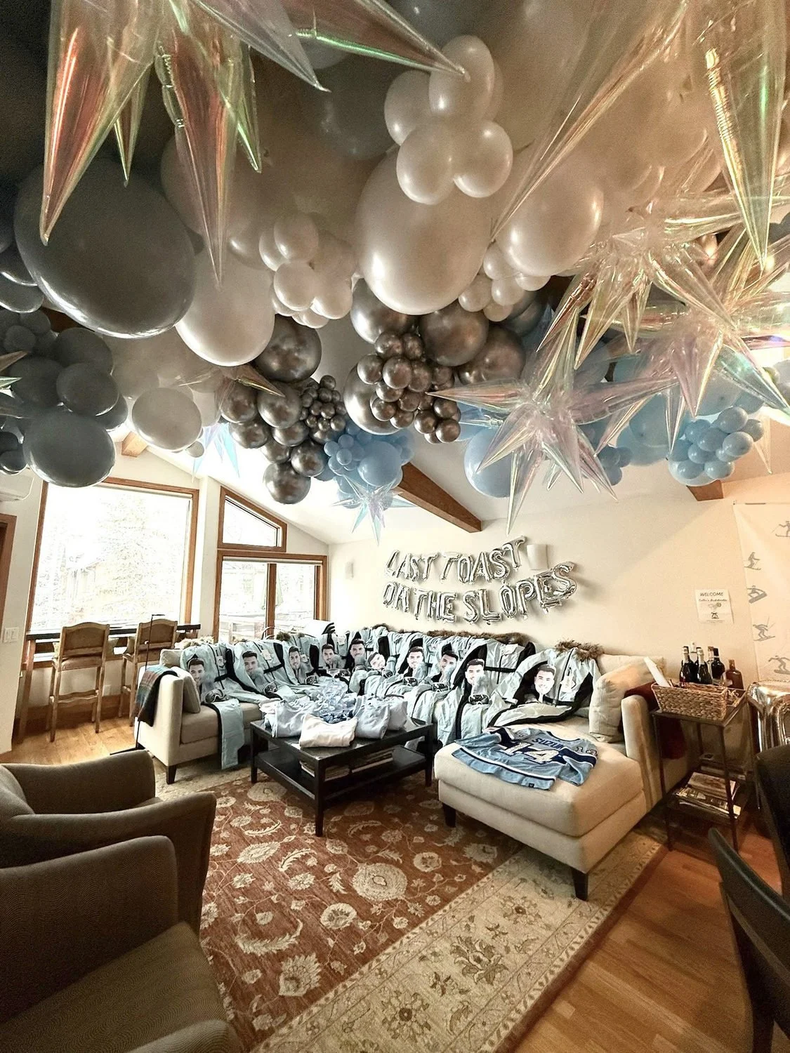 Living room decorated with silver and black balloons, star ornaments and bachelorette party favors.