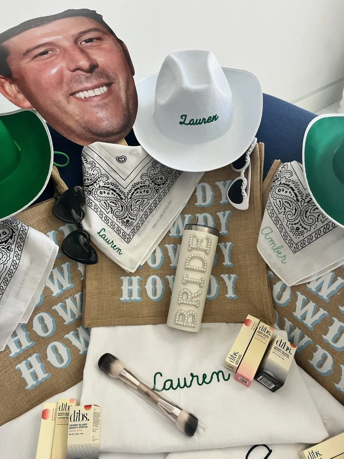 Western-themed bachelorette favors with personalized cups, bandanas, a cowboy hat and a groom-face cutout.