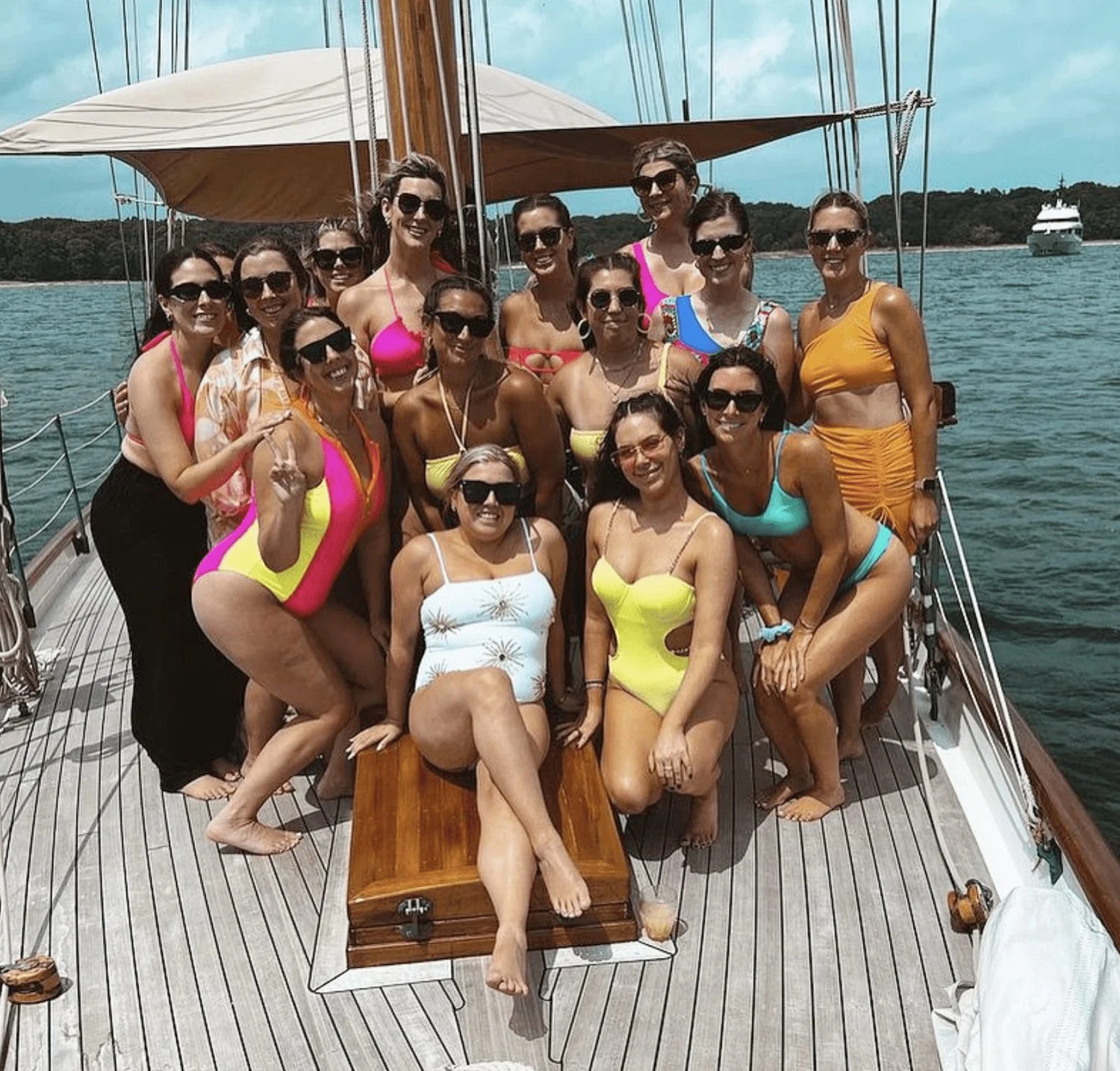 Bachelorette group in colorful swimsuits posing on the deck of a sailboat.