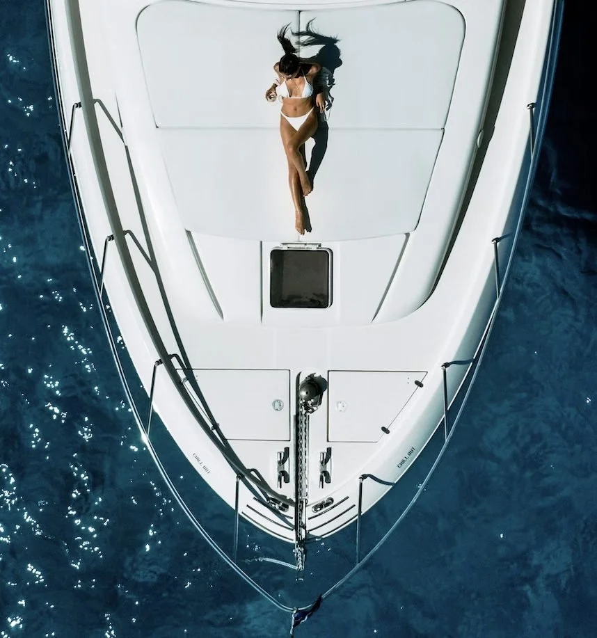 Overhead view of a woman reclining on the bow of a white yacht.