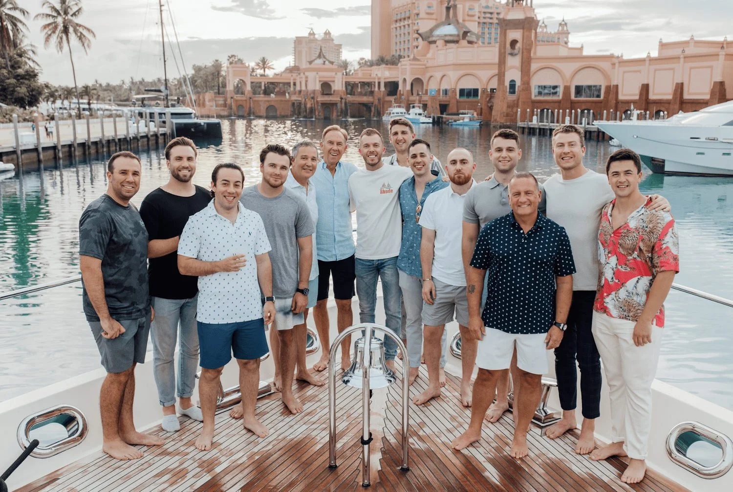 Bachelor party group posing on the deck of a yacht in a marina.
