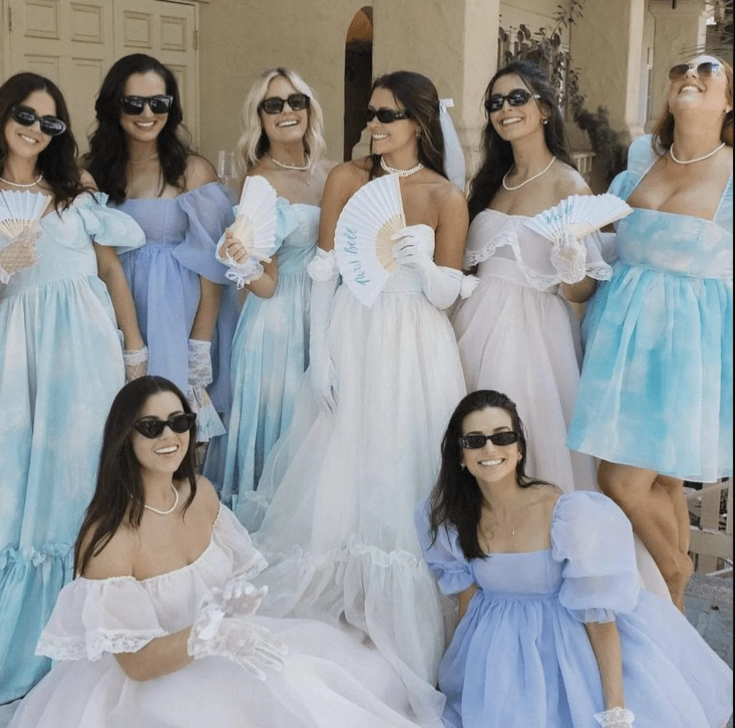 Bachelorette group in blue and white dresses and sunglasses posing together.