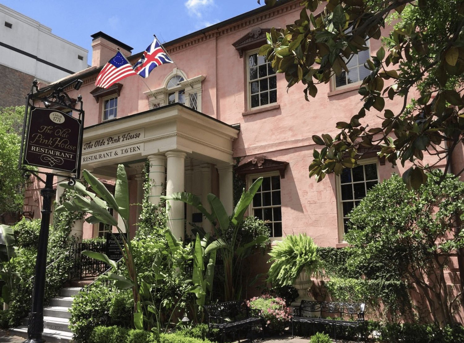 Pink historic building with a columned entrance and flags in Savannah.
