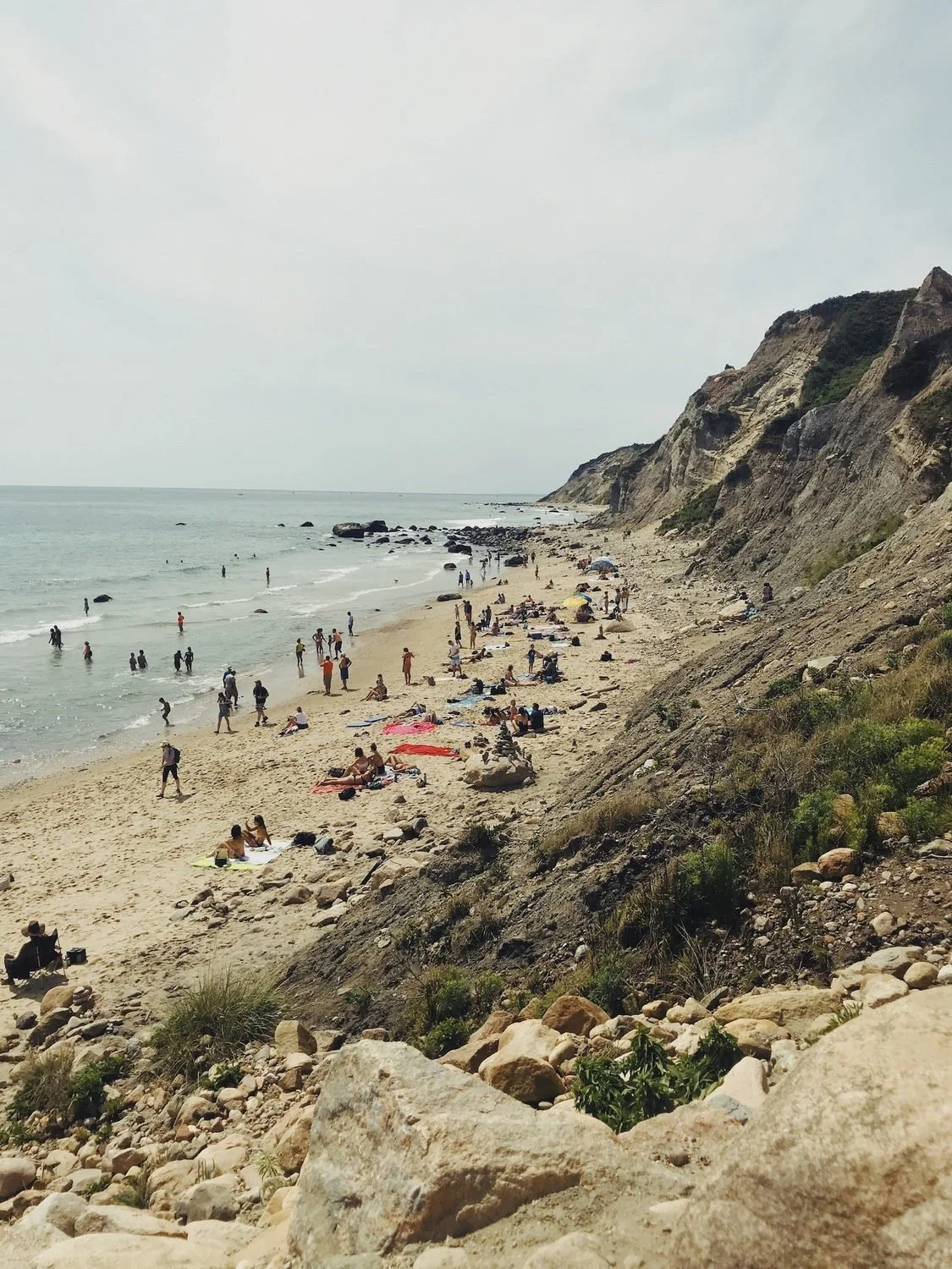Beachgoers along the shoreline beneath the cliffs of Block Island.