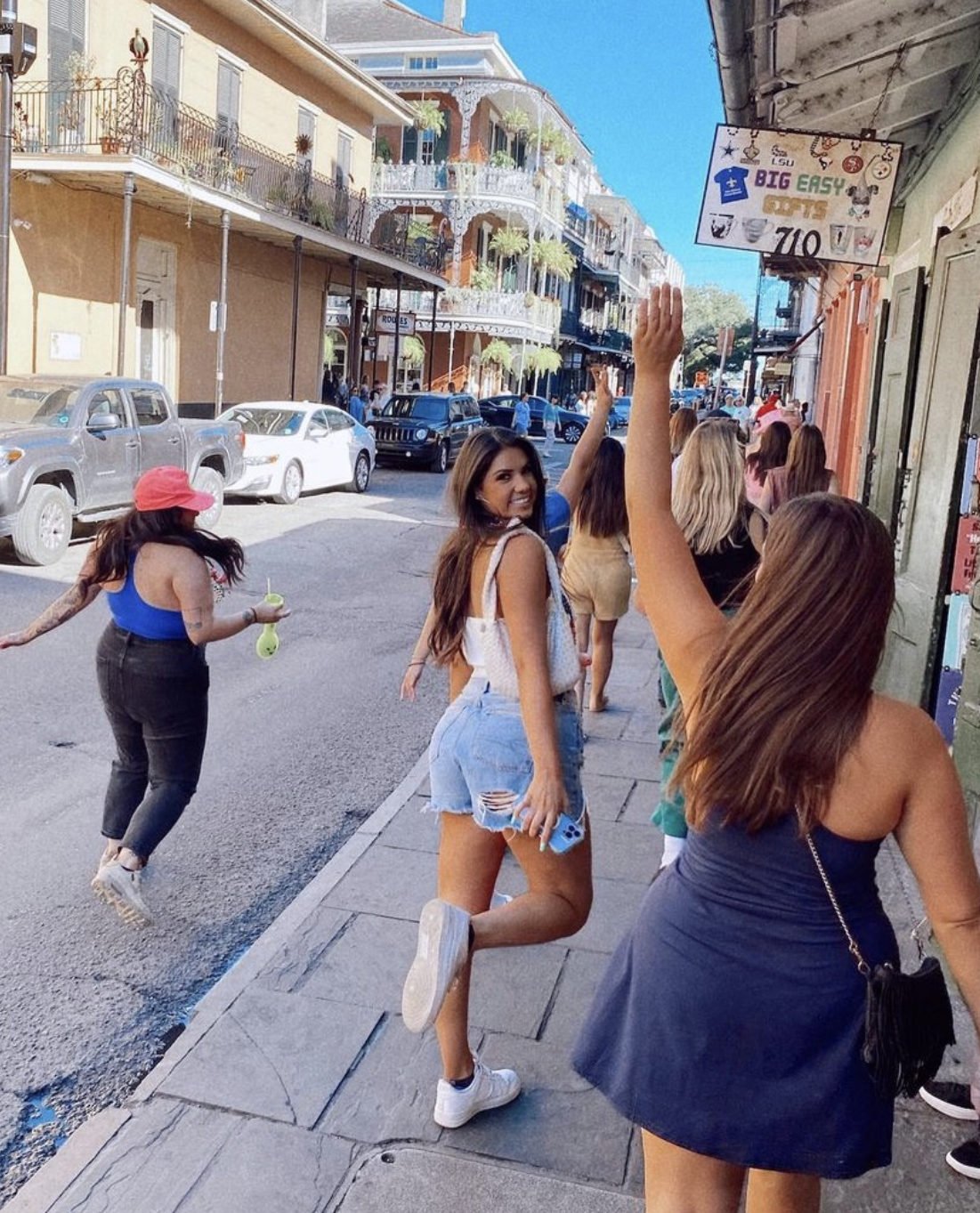 Friends celebrating on a New Orleans street lined with wrought-iron balconies.