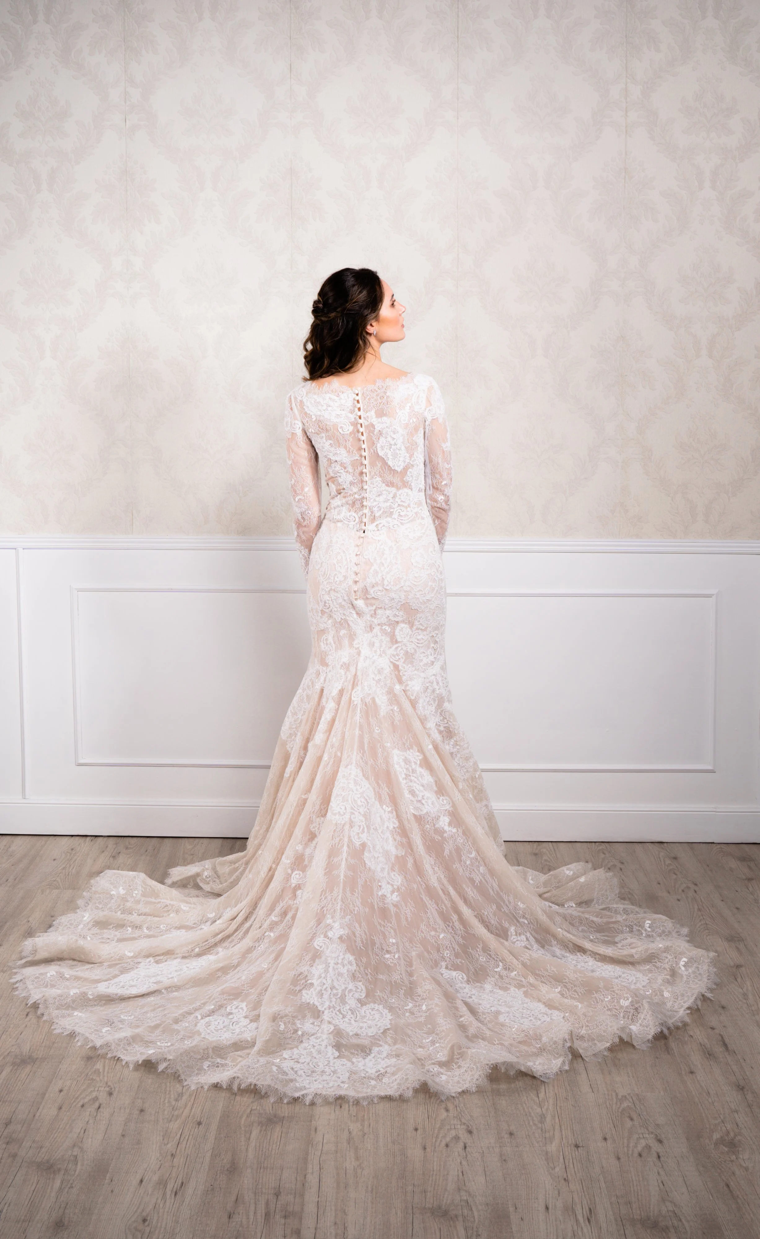 Vestido de corte sirena elaborado en tul bordado con encaje, manga larga y cierre con botonadura decorativa hasta la cola.