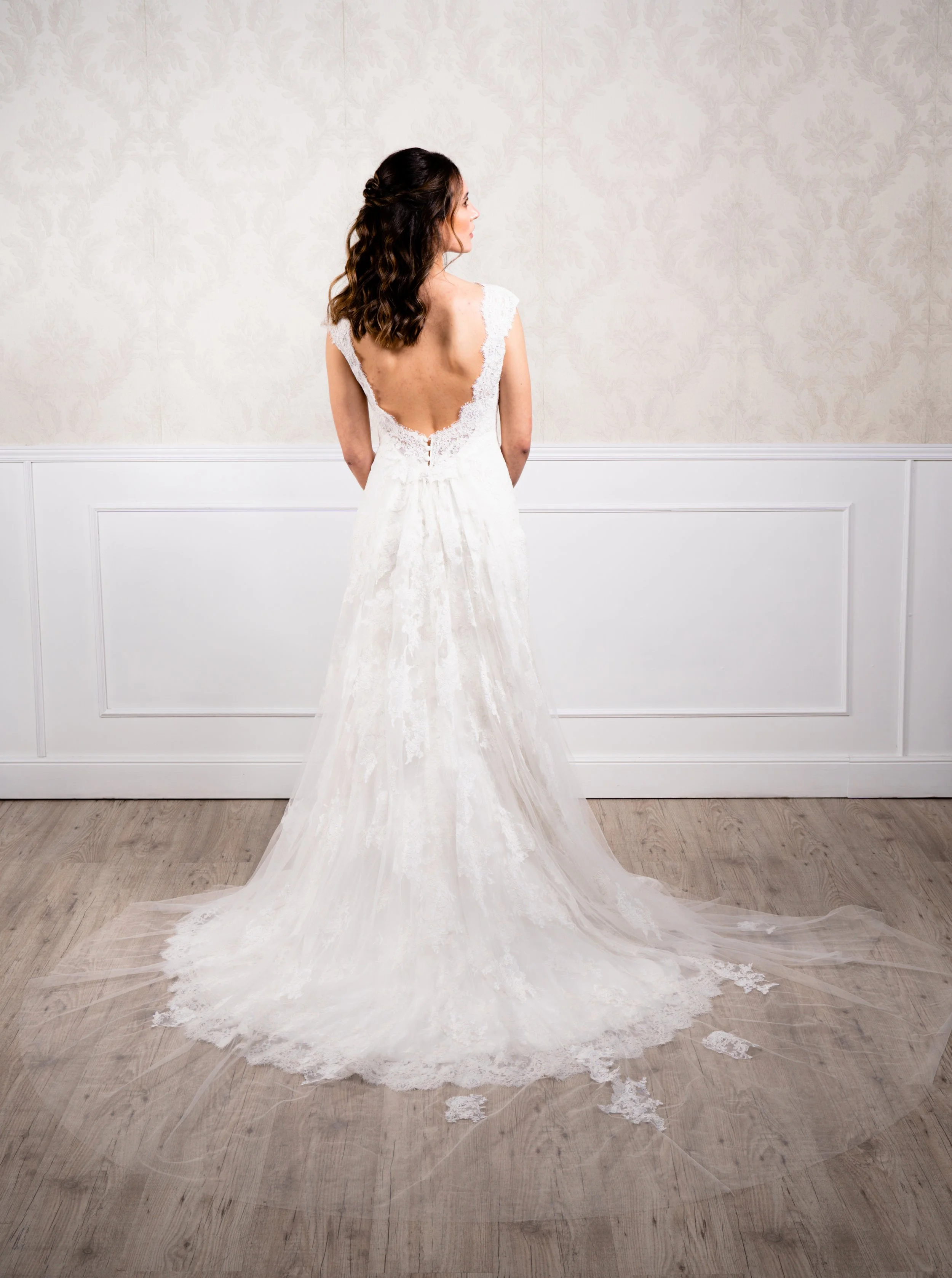 Vestido de silueta sirena elaborado con encaje de algodón blanco, tirante ancho y cola desmontable.