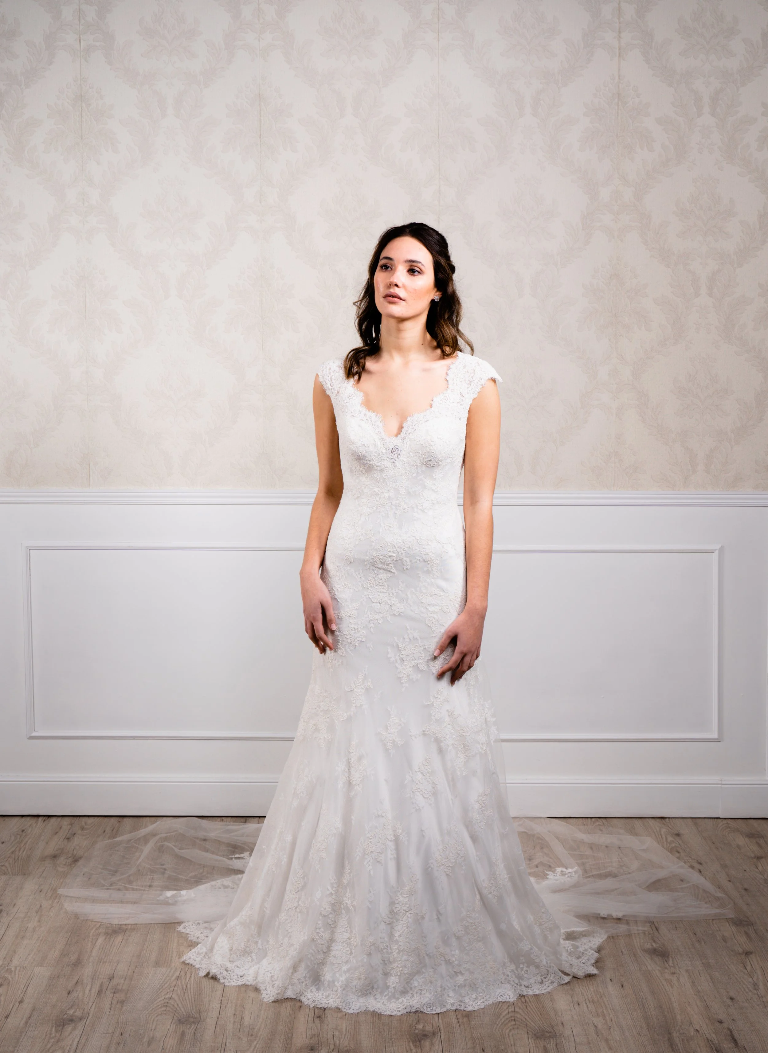 Vestido de silueta sirena elaborado con encaje de algodón blanco, tirante ancho y cola desmontable.