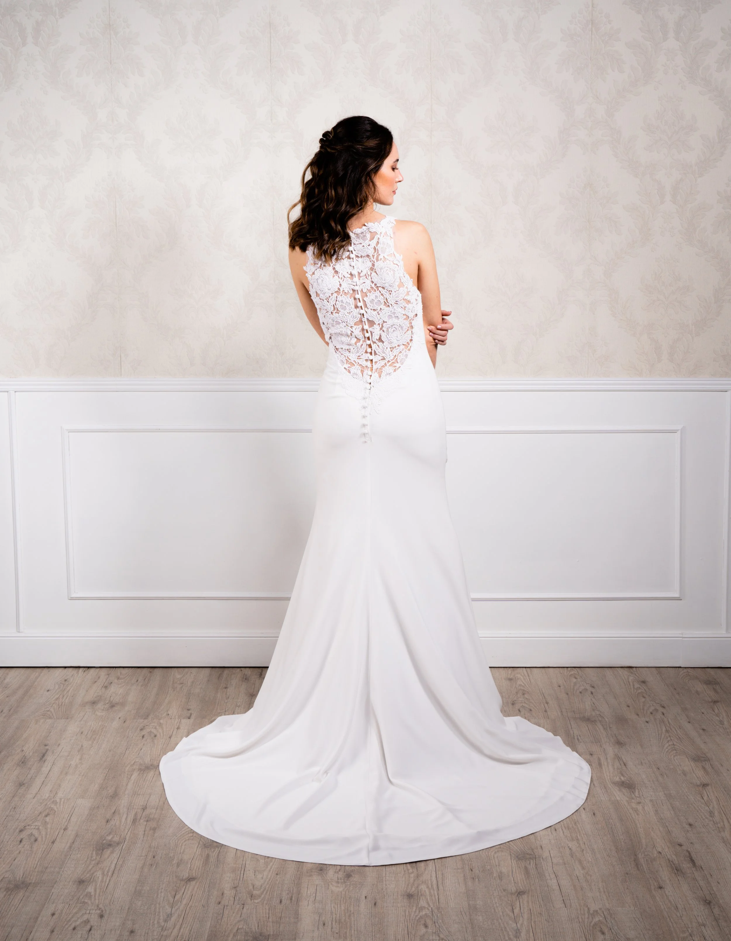 Vestido de corte sirena elaborador en crep suave y espalda bordada con encaje de algodón natural, escote halter y botonadura decorativa hasta la cola.
