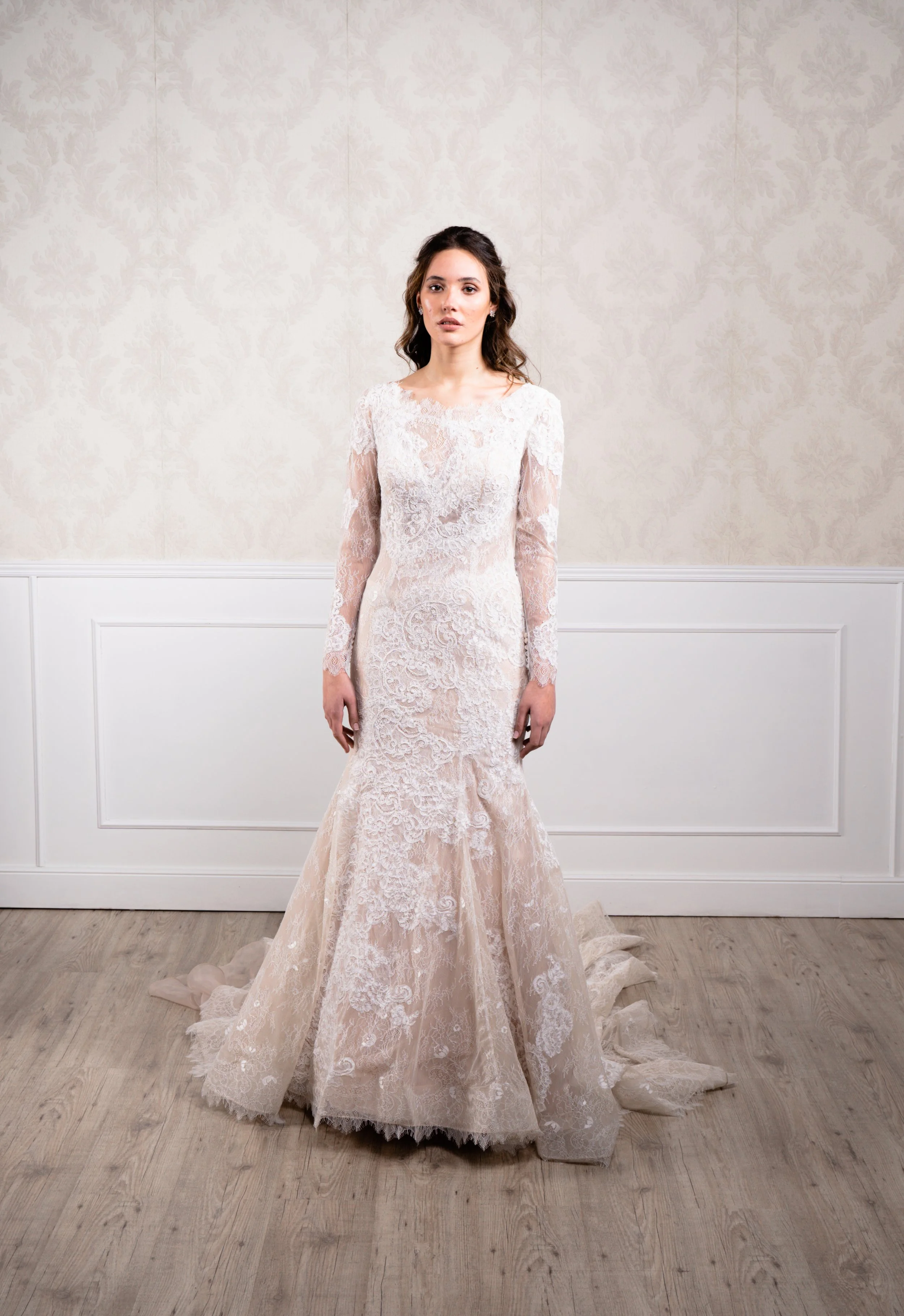 Vestido de corte sirena elaborado en tul bordado con encaje, manga larga y cierre con botonadura decorativa hasta la cola.