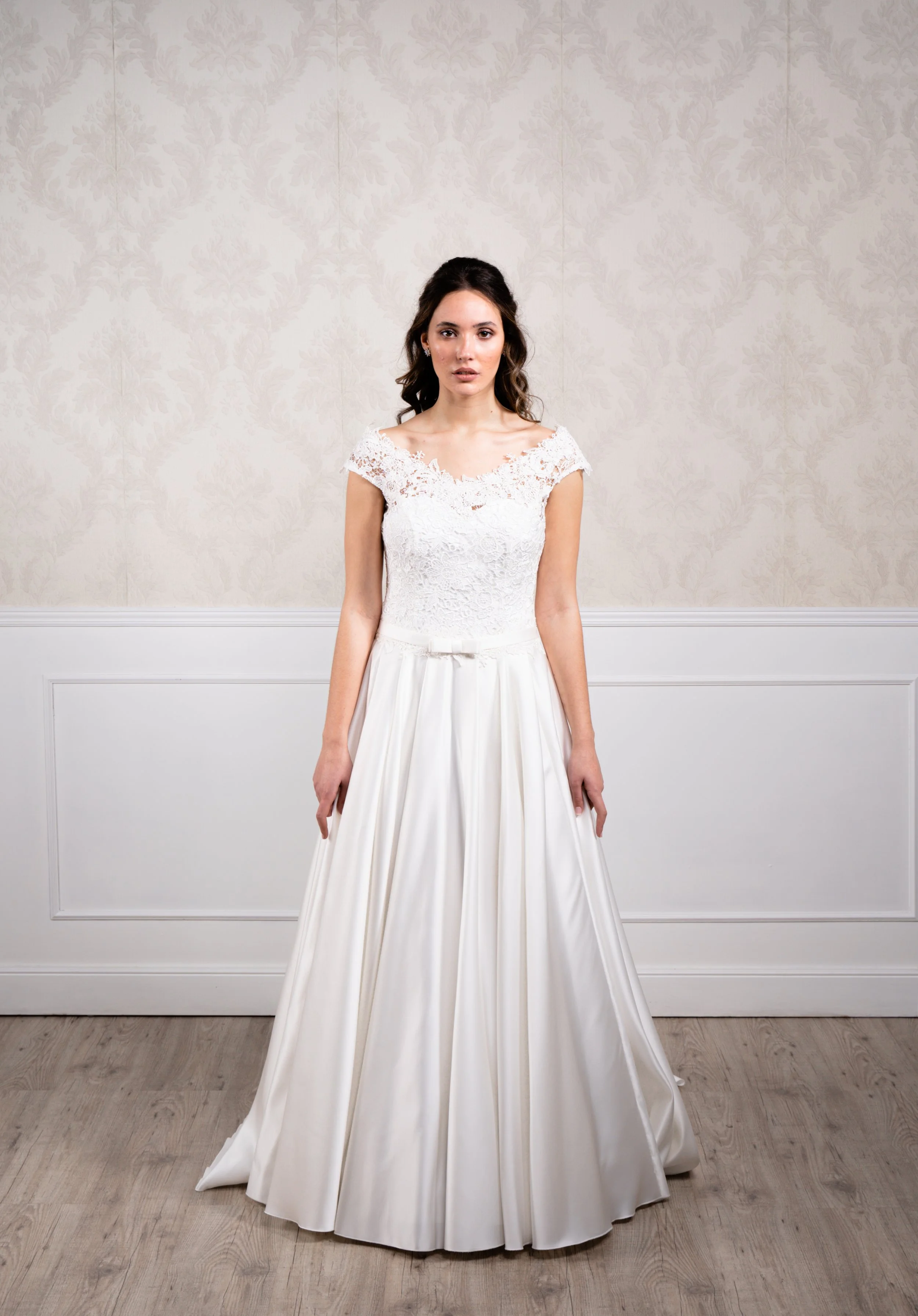 Vestido de corte princesa elaborado con tafetán en la base de la falda y encaje de algodón en el cuerpo, escote en forma de barco y cierre con botonadura.