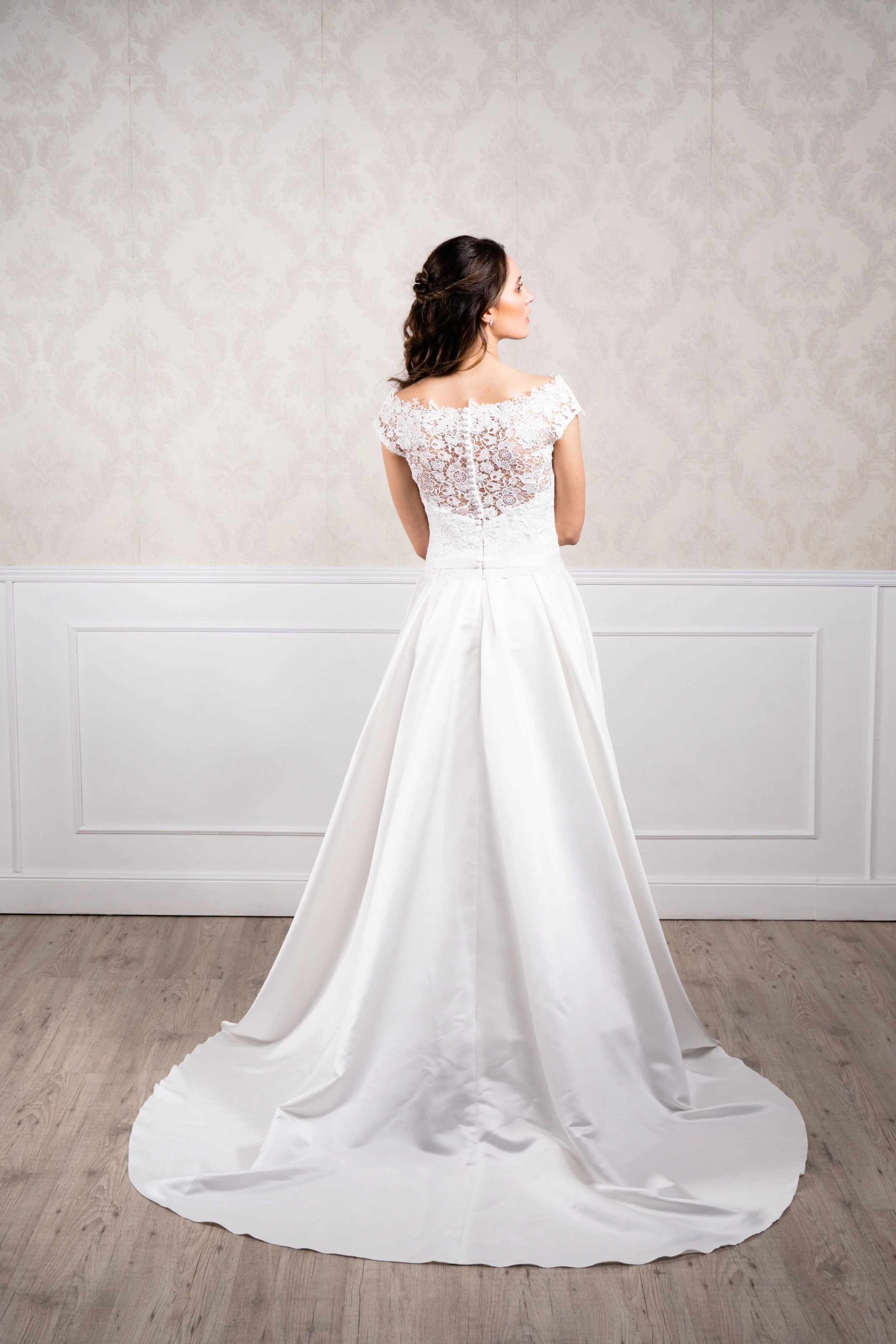 Vestido de corte princesa elaborado con tafetán en la base de la falda y encaje de algodón en el cuerpo, escote en forma de barco y cierre con botonadura.