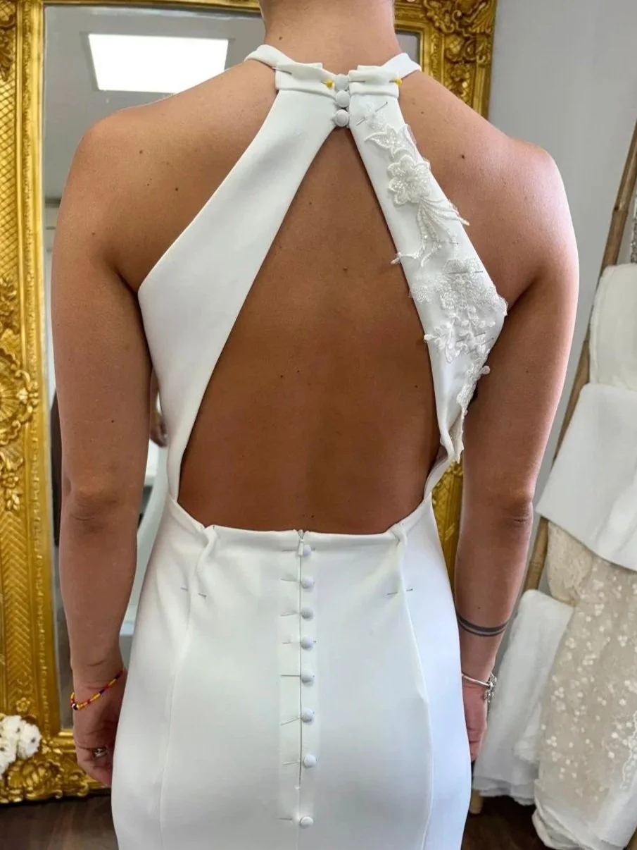 Vestido de novia blanco con abertura en la espalda y botones en la parte trasera.