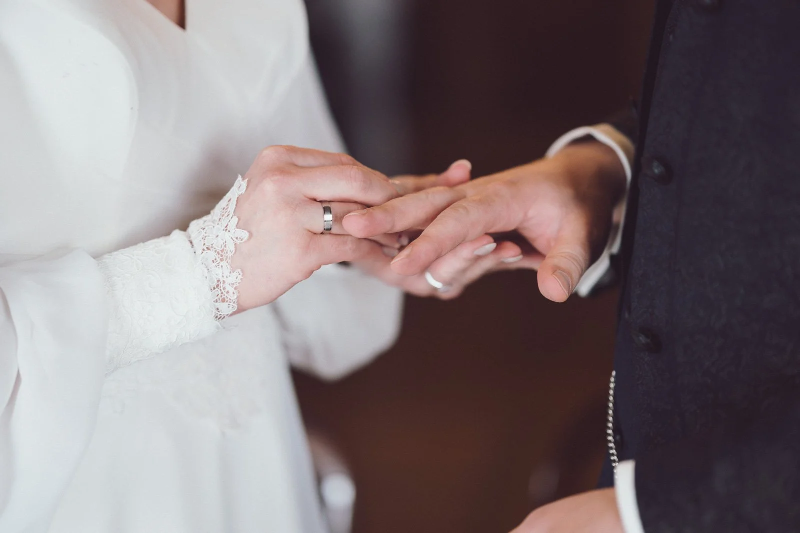 Nahaufnahme eines Heiratsantrags mit Händen, Verlobungsringe und Brautkleid.