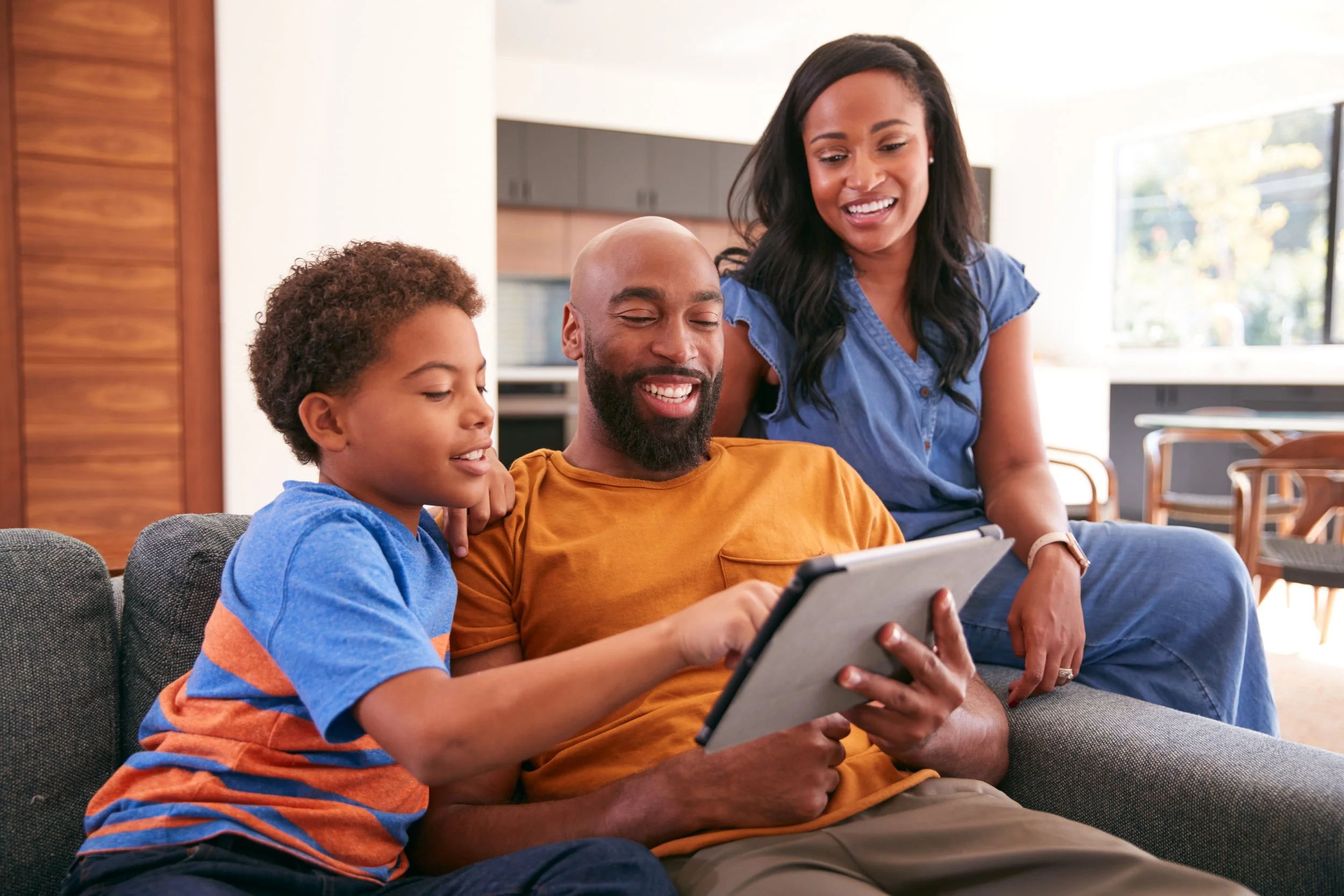 Two foster parents teach a child about digital safety on a tablet.