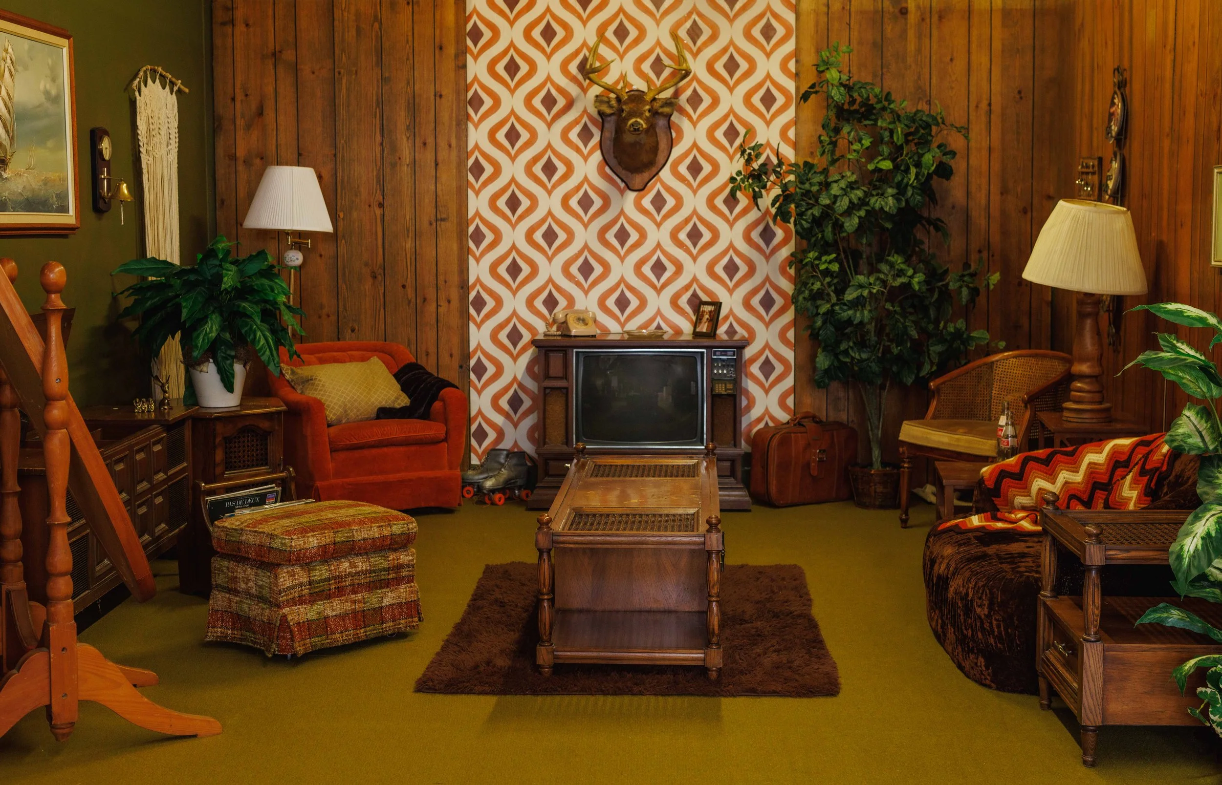 70s retro living room photography set featuring orange patterned wallpaper, vintage television, wood paneling, green walls, mid century furniture, shag rug, and nostalgic decor at Studio Ethereal