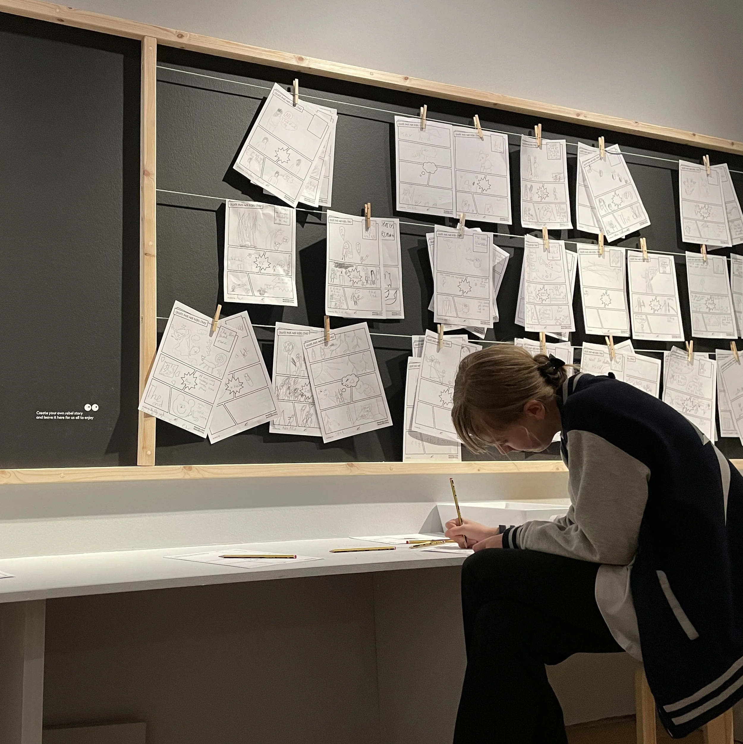 A child trying on the costume of the main character from "Where the Wild Things Are" - a grey cloak with a cardboard fur-lined crown.