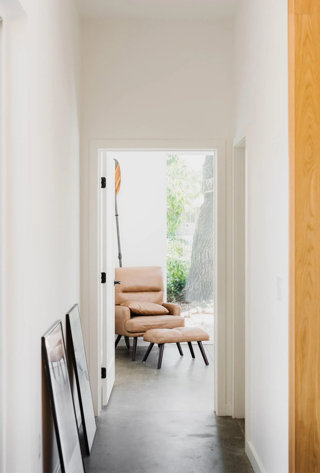 Looking down a hallway towards the back bedroom of an ADU with a brown chair and large windows.