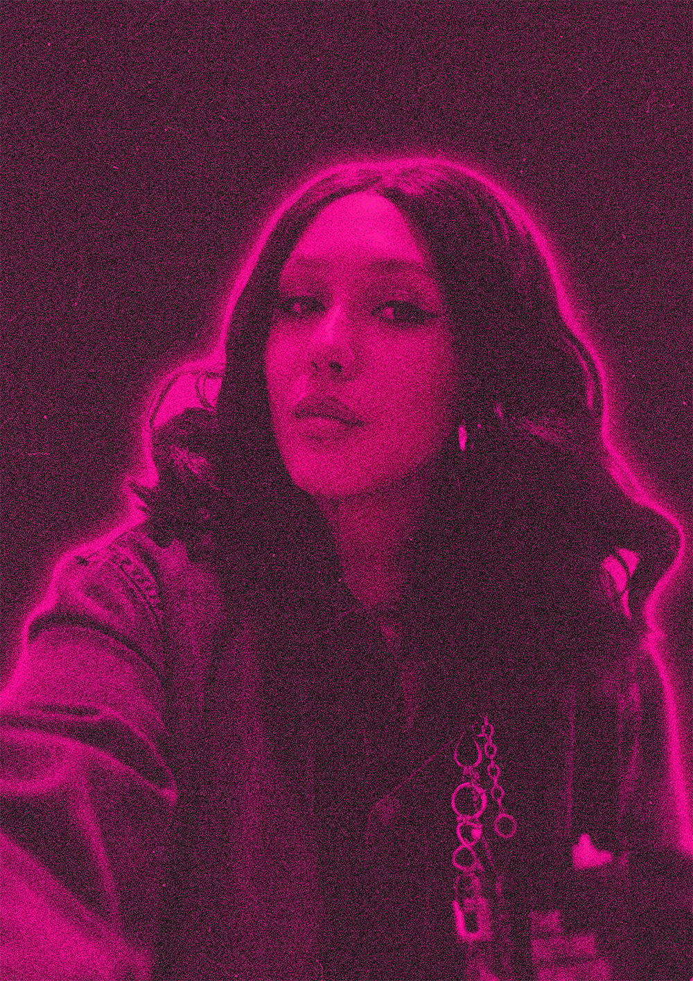 A woman with long wavy hair looking at the camera, surrounded by pink neon light, with a dark background.